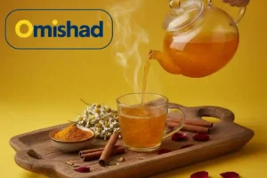 دمنوش زردچوبه اعلای ۲۰۰ گرمی امیشاد در فنجان شیشه‌ای همراه با چوب دارچین و گل بابونه