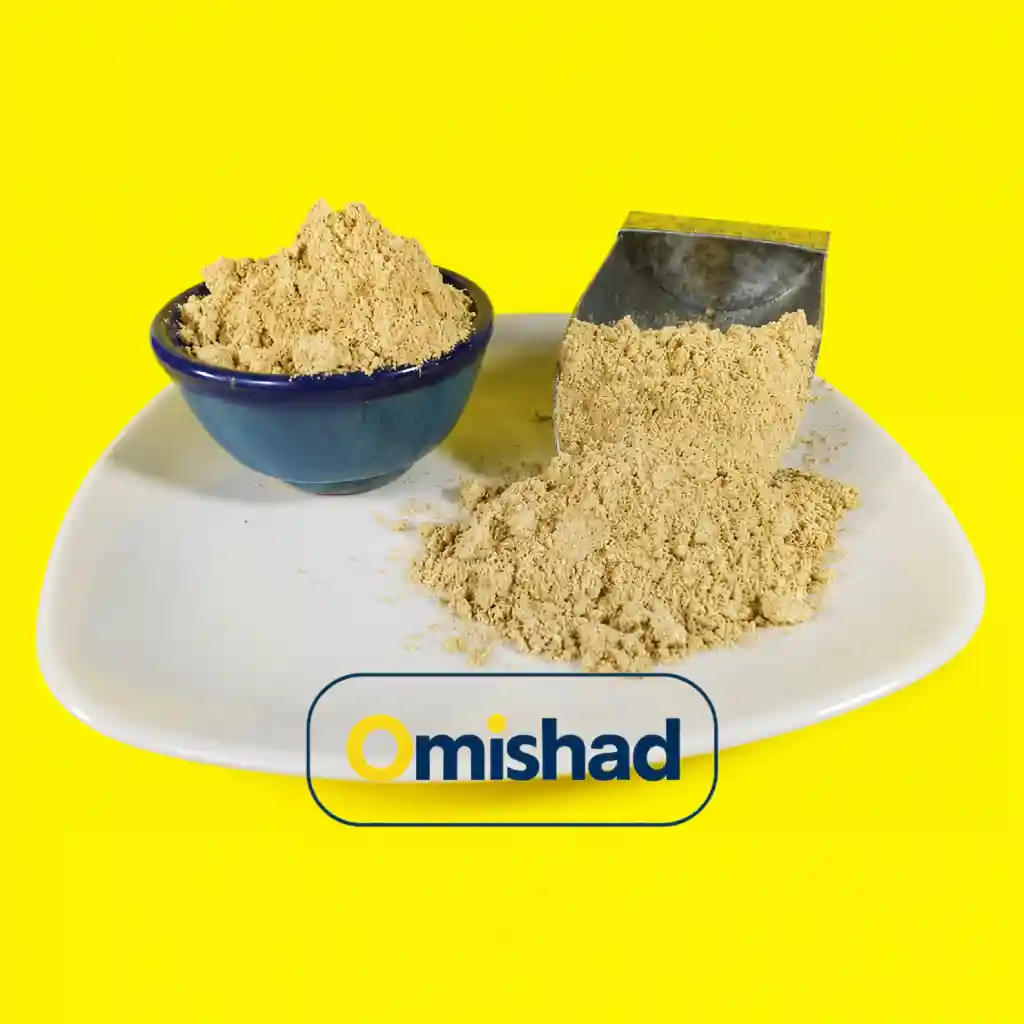 زنجبیل نرم آسیاب شده بسته 200 گرمی 1 پودر زنجبیل آسیابشده روشن در کاسه آبی و روی بشقاب سفید کنار پیمانه فلزی با پسزمینه زرد.
