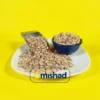 لوبیا چیتی خمین داخل کاسه و سر تاس فلزی روی بشقاب سفید با پس‌زمینه زرد.