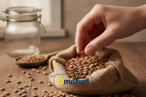 عدس خارجی روس بسته 900 گرمی 4 دست در حال برداشتن عدس خارجی روس بسته 900 گرمی امیشاد از کیسه کنفی روی میز چوبی کنار قاشق و شیشه شفاف.