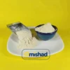 پودر پیاز اعلا در ظرف آبی و بیلچه فلزی روی بشقاب سفید.