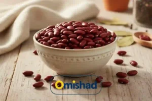 کاسه سرامیکی کرم‌رنگ پر از لوبیا قرمز خمین دست چین عمده 30 کیلویی روی میز چوبی روشن با نور طبیعی و پس‌زمینه پارچه سفید.