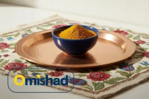 زردچوبه عمده 5 زردچوبه فله امیشاد در کاسه آبی روی سینی مسی و پارچه گلدار ایرانی در نور گرم محیط.