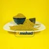 پودر ادویه سمبوسه زرد-قهوه‌ای روی بشقاب سفید، کنار کاسه سرامیکی آبی و پیمانه فلزی با پس‌زمینه زرد.