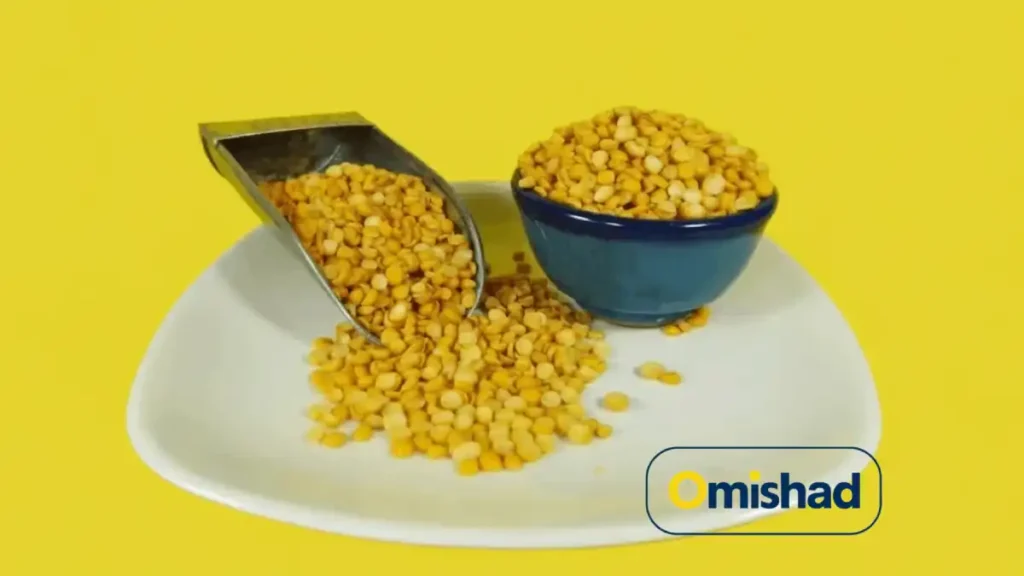 کاسه و پیمانه فلزی پر از لپه زرد تازه امیشاد روی پس‌زمینه زرد روشن، نماد کیفیت و تازگی محصول.