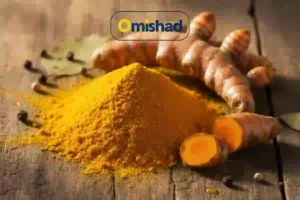 دانشنامه زردچوبه 3 پودر زردچوبه نرم و قلم تازه امیشاد روی میز چوبی با ریشههای برشخورده زردچوبه.