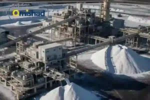 نمای هوایی از کارخانه صنعتی تولید نمک امیشاد با توده‌های بزرگ نمک سفید و خطوط انتقال فلزی. برای مقاله افزایش قیمت نمک