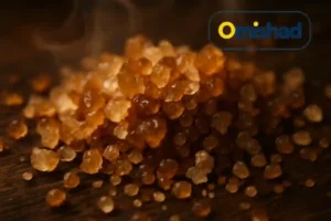 بلورهای طلایی و کهربایی نمک دودی امیشاد روی سطح چوبی تیره با بخار ملایم دود.