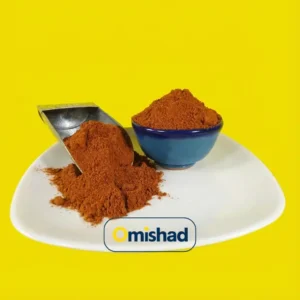 همه چیز راجعبه ادویه 12 پودر فلفل قرمز نرم اعلا ایرانی بسته 200 گرمی در کاسه آبی و پیمانه فلزی روی بشقاب سفید با زمینه زرد.