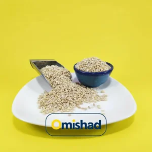 گندم پوست‌کنده حلیمی اطلس اصفهان در بشقاب سفید همراه اسکوپ فلزی و کاسه آبی روی پس‌زمینه زرد.